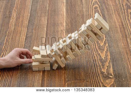 Close-up hands of man pulls out wooden bricks. Removing blocks from a tower. Keeping balance. Full concentration. Entertainment activity. Game of physical and mental skill. Close-up photo.