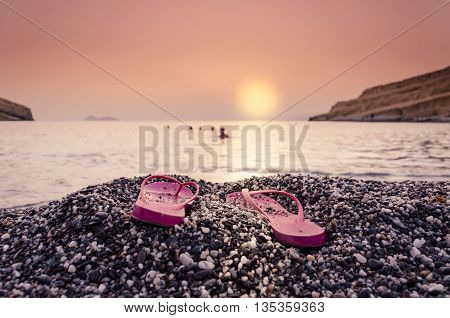 Sunset with woman's  sandals on the beach
