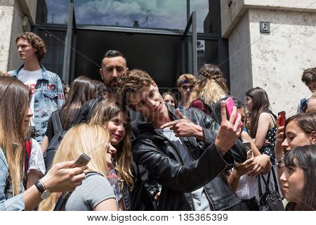 MILAN ITALY - JUNE 19: Beautiful model takes a selfie with some girls outside Ferragamo fashion show building during Milan Men's Fashion Week on JUNE 19 2016 in Milan.