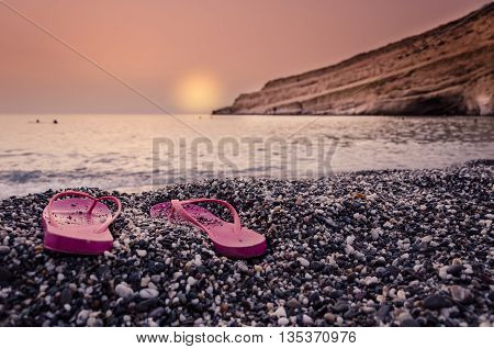 Sunset with woman's  sandals on the beach