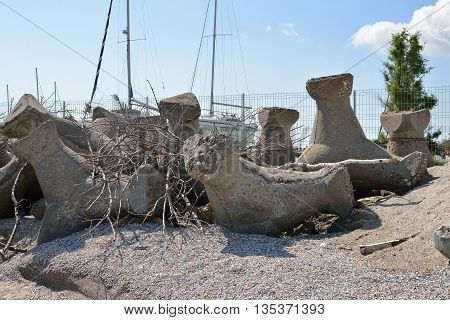 Close Up Of Old And Broken Tetrapods Made Of Concrete Buried In Sand At The Beach, Need To Yacht Har