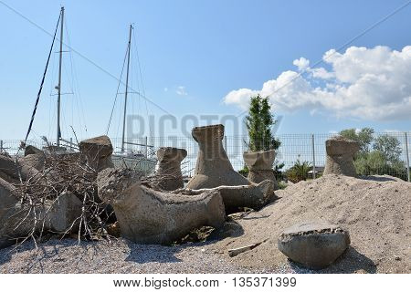 Close Up Of Old And Broken Tetrapods Made Of Concrete Buried In Sand At The Beach, Need To Yacht Har