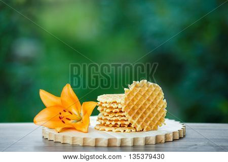 Belgian waffles with fresh berries on cutting board on background of green bokeh