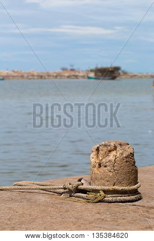 A mooring on a dock in a port keeps an old fishing trawler tethered in place.