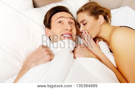 Woman whispering to her husband and he laughting