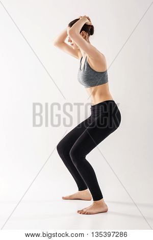 Sporty beautiful young woman practicing Uddiyana Bandha technique in white room