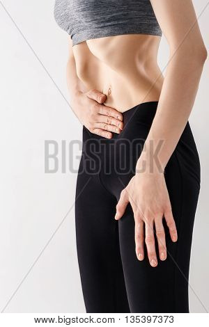 Sporty beautiful young woman practicing Uddiyana Bandha technique on the white background