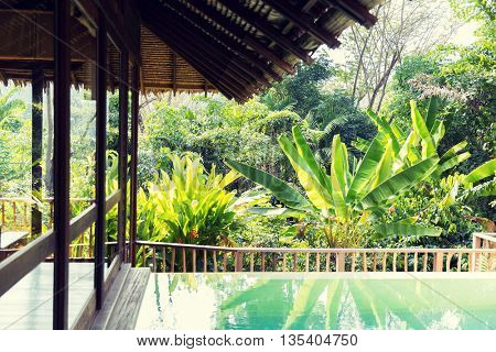 leisure, travel and tourism concept - swimming pool and bungalow at hotel resort
