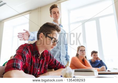 education, bullying, social relations and people concept - classmate offending at student boy at school