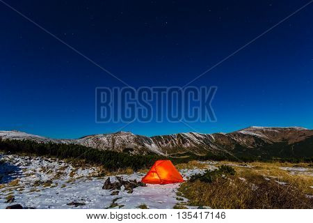 Winter Camping Orange Glowing Tent in Mountain Landscape and Night Sky with Many Stars Red Tent and Snowy Terrain