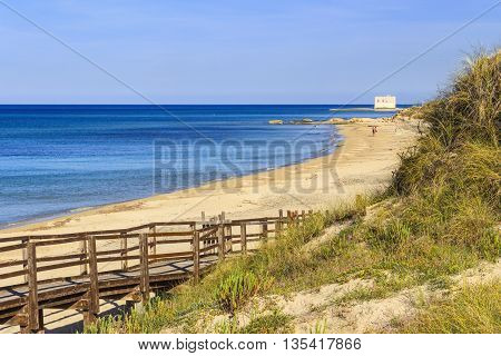 The Regional Natural Park Dune Costiere (Torre Canne): wooden walkway between sea dunes. (Apulia)-ITALY- The park covers the territories of Ostuni and Fasano along eight kilometers of coastline.Beach with sea dunes in the background an angler.