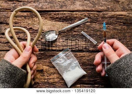 drug addict holding syringe and tourniquet closeup