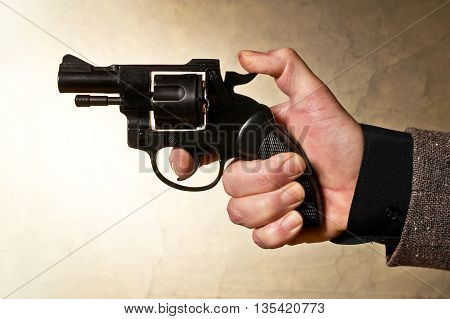 Silhouette of a mans hand with a handgun in brown