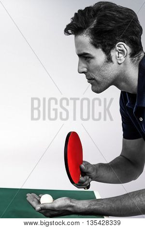 Confident male athlete playing table tennis against grey background