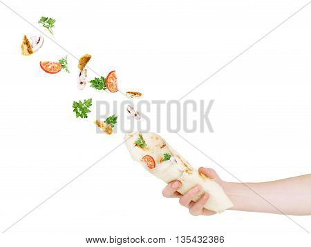 Vegetables fly to pita bread which keeps a hand on a white background
