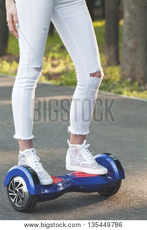 Girl using a self-balancing two-wheeled board. The gyroscope based dual wheel electric scooter is also called a smart balance wheel. Feet on hover board scooter