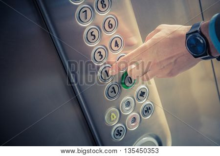 Male finger pressing the first floor button in the elevator