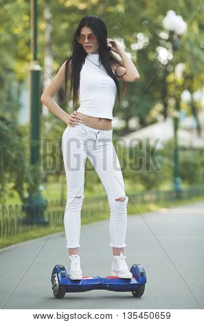 Young sexy fit woman in white riding hoverboard - electrical scooter, personal eco transport, gyro scooter, smart balance wheel