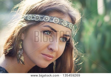 Portrait of a young female hippie with headband and earrings