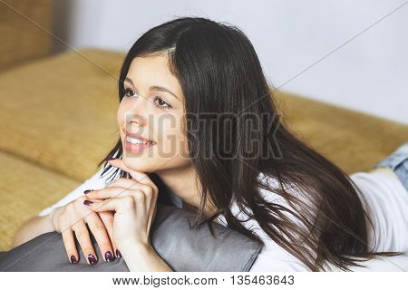 Relaxing woman sitting comfortable in sofa lounge chair smiling happy looking at camera. Portrait of a beautiful young healthy woman relaxing