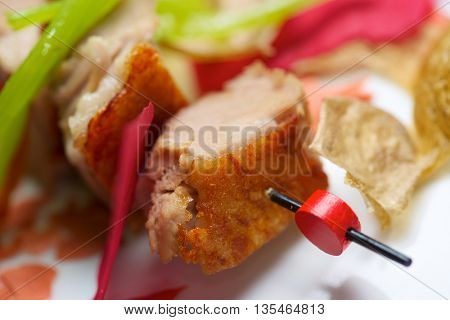 Closeup of a skewer of pork jowls.