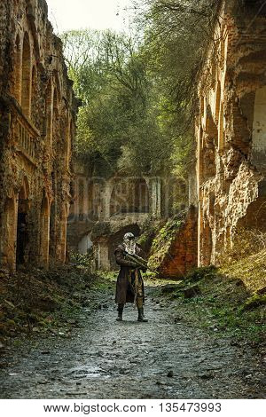 Nuclear post-apocalypse. Sole survivor in tatters and gas mask on the ruins of the destroyed city