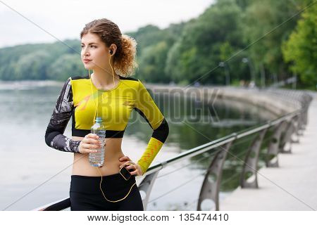 Sporty caucasian girl resting in the Park after Jogging with a plastic bottle of water