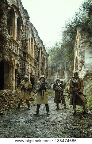 Nuclear post-apocalypse. Survivors in tatters and gas mask on the ruins of the destroyed city