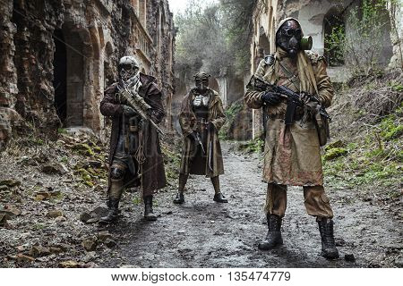 Nuclear post-apocalypse. Survivors in tatters and gas mask on the ruins of the destroyed city
