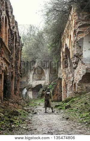 Nuclear post-apocalypse. Sole survivor in tatters and gas mask on the ruins of the destroyed city