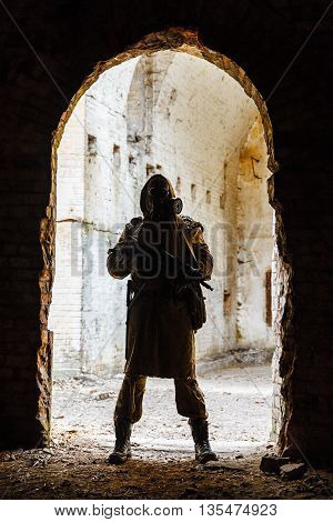 Nuclear post-apocalypse. Sole survivor in tatters and gas mask on the ruins of the destroyed city