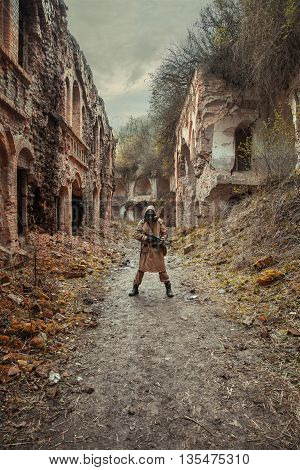 Nuclear post-apocalypse. Sole survivor in tatters and gas mask on the ruins of the destroyed city