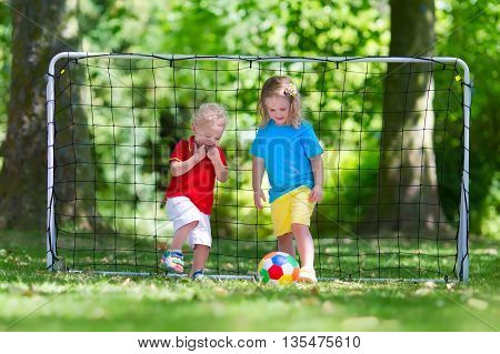 Two happy children playing European football outdoors in school yard. Kids play soccer. Active sport for preschool child. Ball game for young kid team. Boy and girl score a goal in football match.