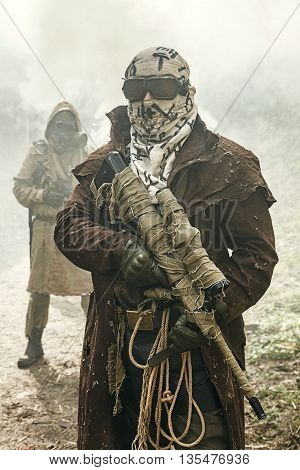 Nuclear post-apocalypse. Survivors in tatters and gas mask on the ruins of the destroyed city