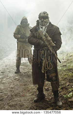 Nuclear post-apocalypse. Survivors in tatters and gas mask on the ruins of the destroyed city