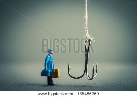 Miniature businessman is staring at fishing needle