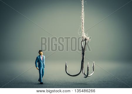 Miniature businessman is staring at fishing needle