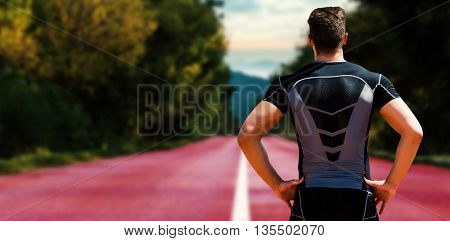 Composite image of sportsman is posing with hands on hips on a race track
