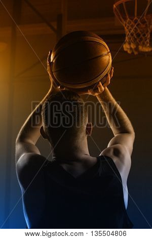 Portrait front the back of basketball player trying to put a basket on a gym