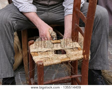Mender Of Chairs While Repairing An Old Wooden Chair With Straw