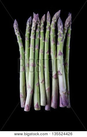 Raw asparagus on black background