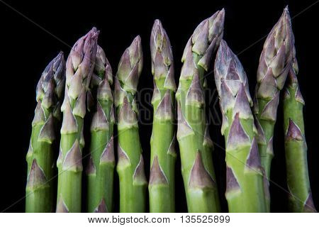 Raw asparagus on black background