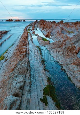 Twilight Ocean Coast With Ribbed Stratiform Rock.