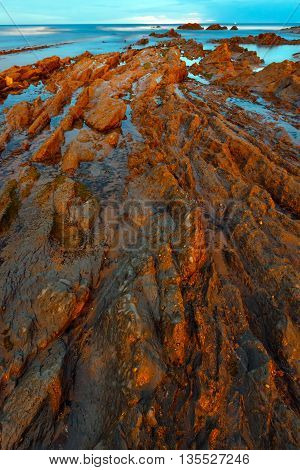 Twilight Ocean Coast With Ribbed Stratiform Rock.
