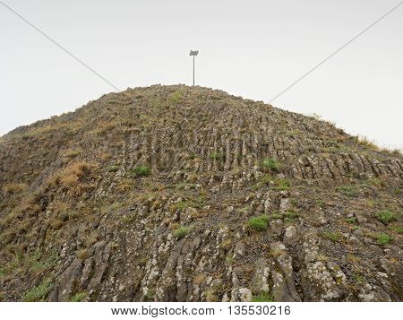 Sharp peak of basalt formation. Long basalt poles of cold volcano.