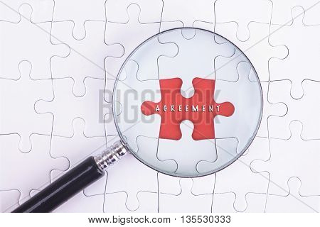 Business Concept - Magnifier Glass on white puzze with AGREEMENT Word