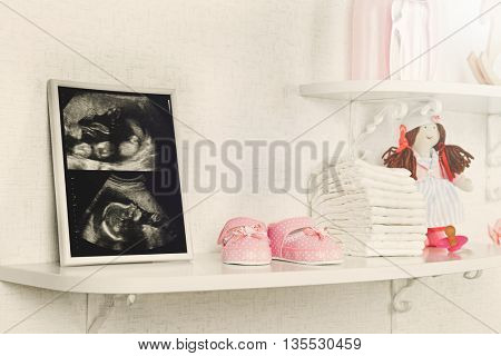 Photo frame with ultrasound scan of baby and accessories on shelves close-up