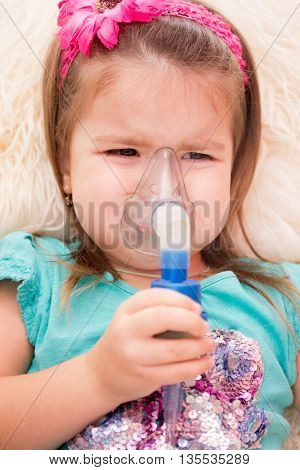 Little girl using an inhaler indoors. nebulizer