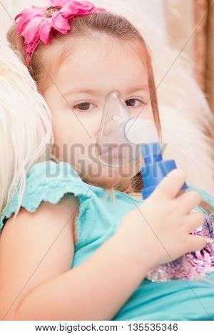 Little girl using an inhaler indoors. nebulizer