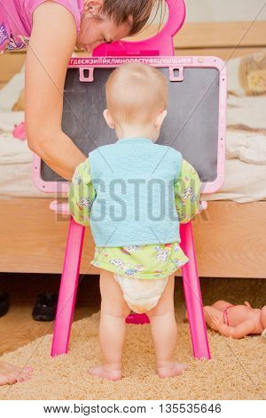 Baby writes letters on a school blackboard